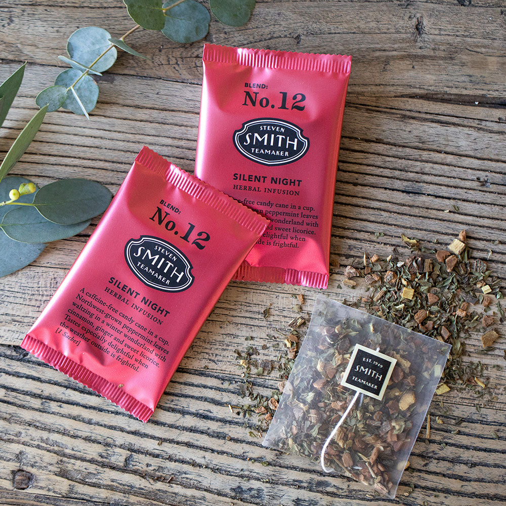 Two red metallic sachets of tea on wooden background.